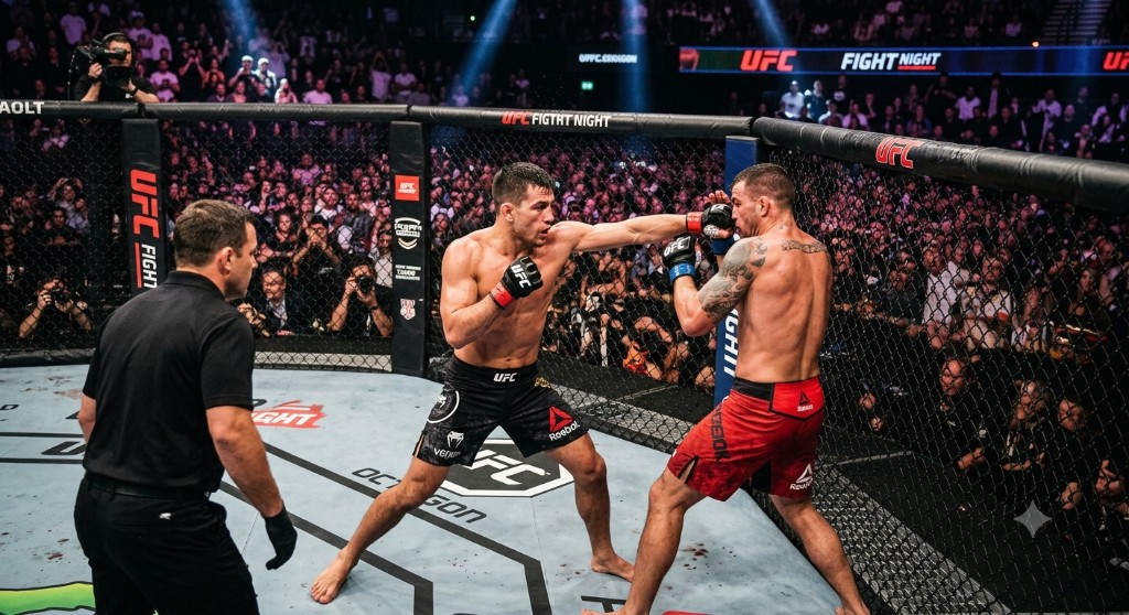 Two MMA fighters exchanging punches inside the cage at a martial arts championship.